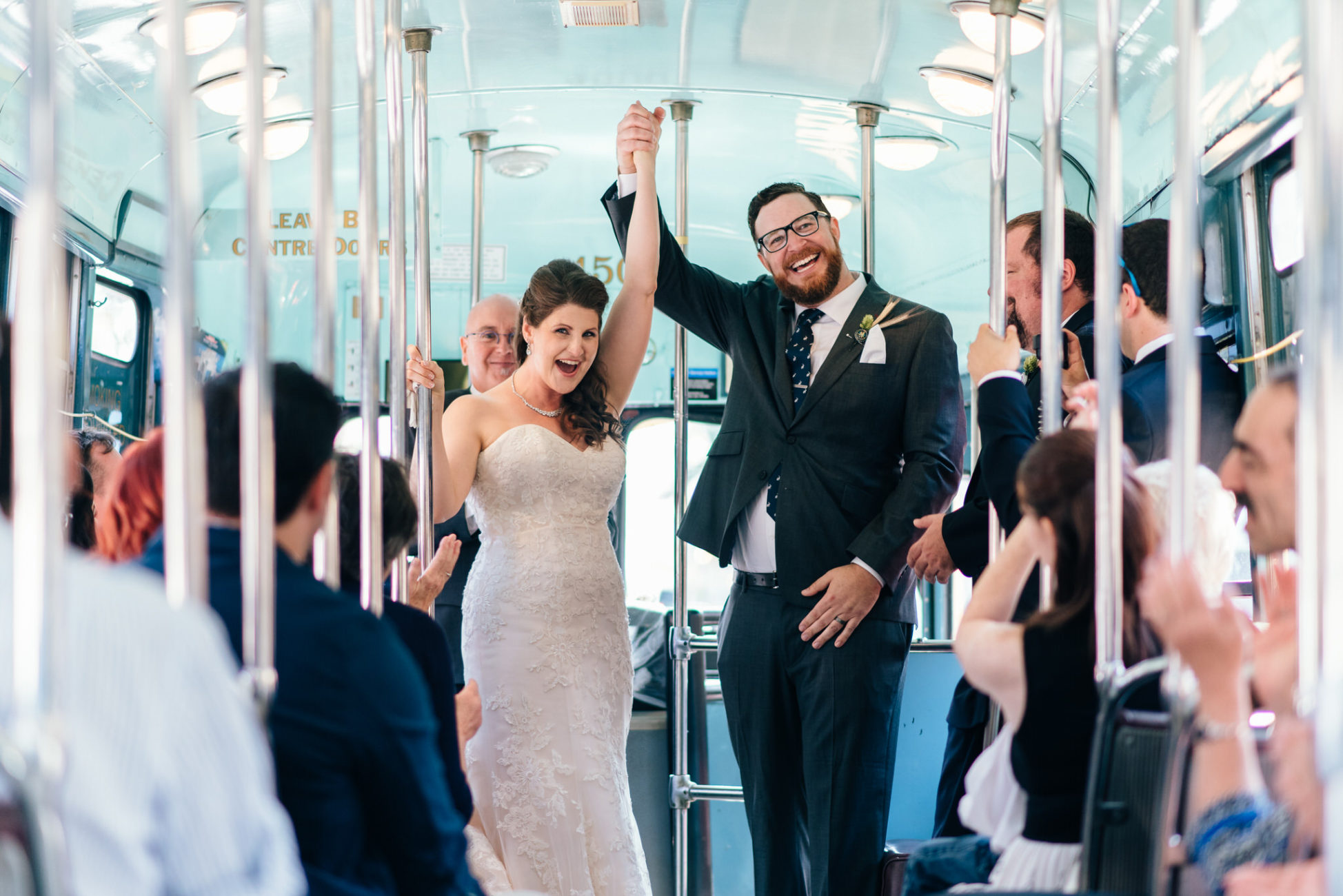 The bride and groom hold their hands in the air in celebration after their Vintage Toronto Streetcar Wedding Ceremony